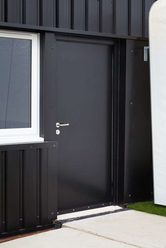 Dark steel thermally insulated door in a brick wall