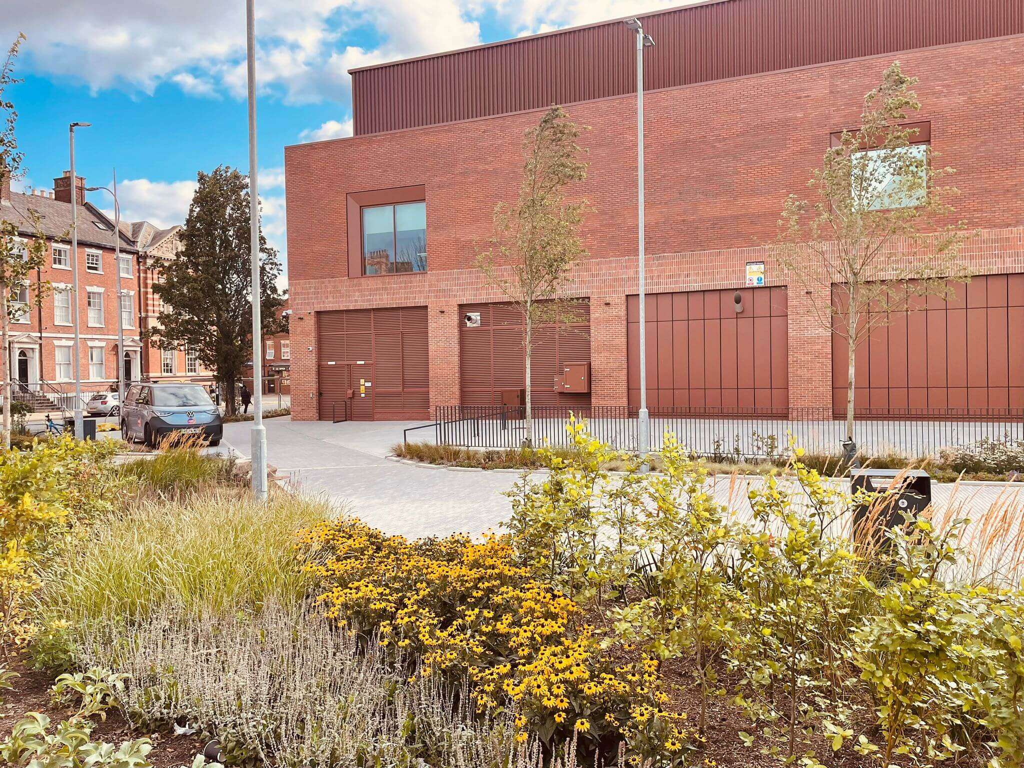 Red brick building with steel roller shutter doors and landscaped entrance