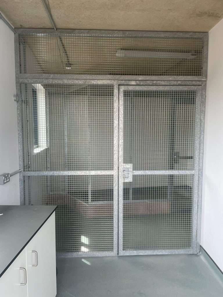 Interior view of a steel-framed animal enclosure with door
